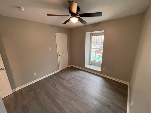 a view of an empty room with window and wooden floor