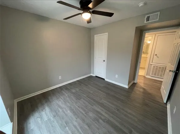 an empty room with wooden floor fan and windows