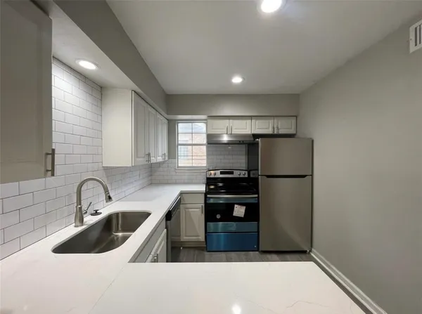a kitchen with a refrigerator sink and white cabinets