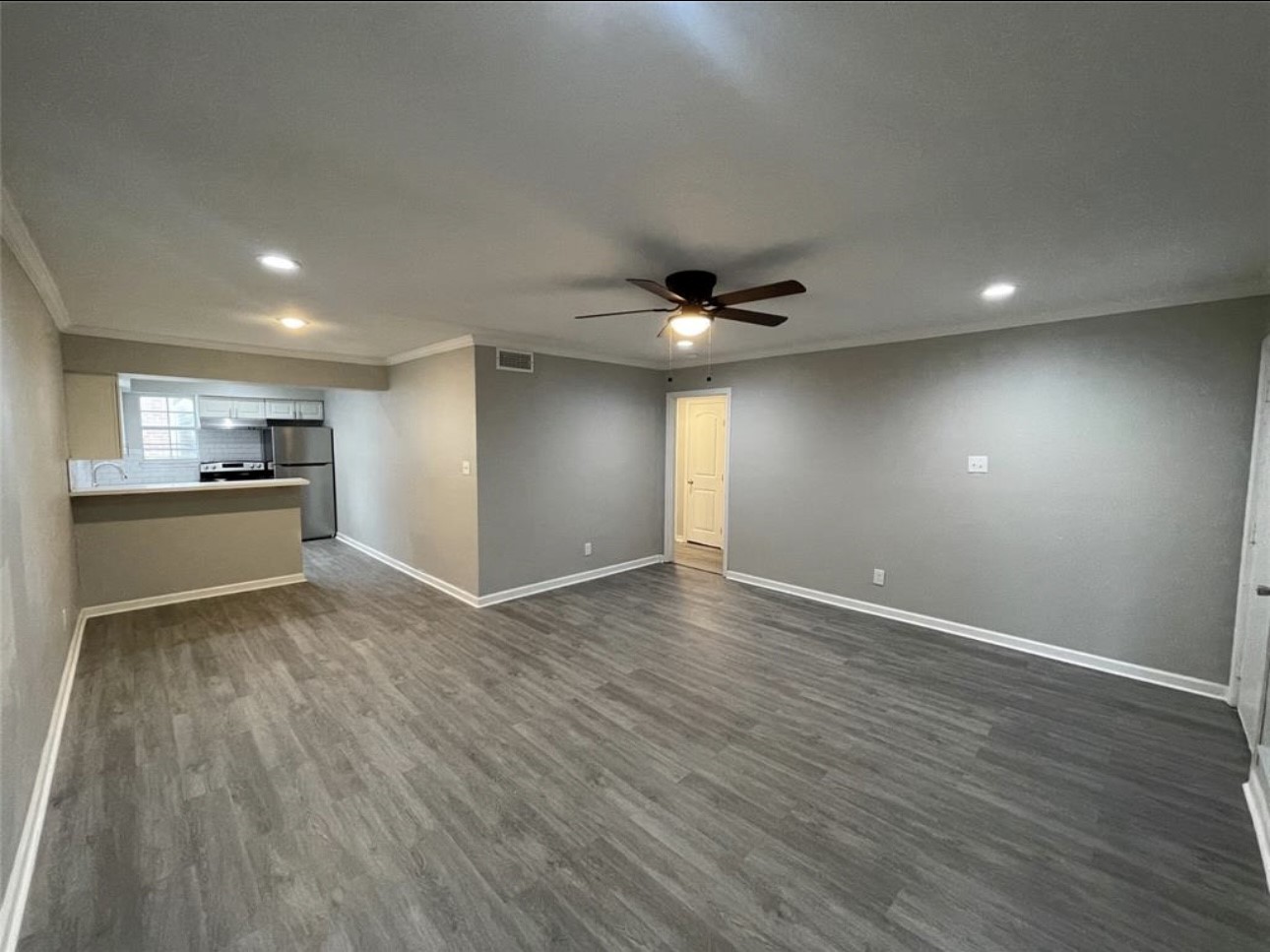 9711 Linkmeadow Lane, Unit 10 Houston, TX 77025 - Photo 4 of 27 a view of an empty room with wooden floor and a kitchen