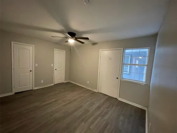 an empty room with wooden floor closet and windows