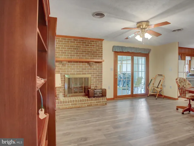 a view of a livingroom with a fireplace a ceiling fan and wooden floor