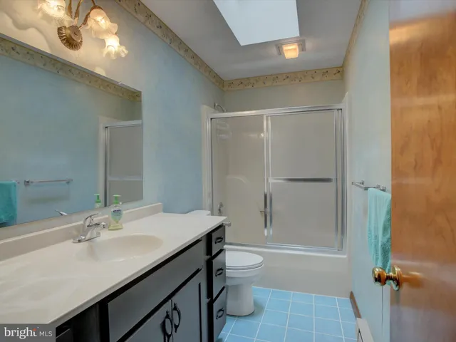 a bathroom with a sink a toilet a mirror and shower