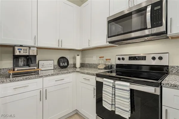a kitchen with granite countertop cabinets stainless steel appliances and white cabinets