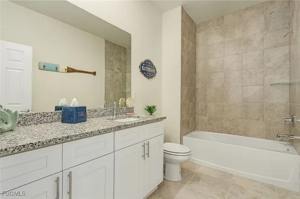 a bathroom with a granite countertop sink a toilet and bathtub