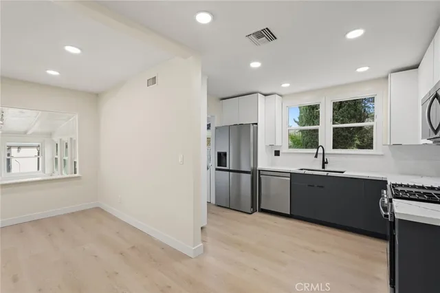 a large white kitchen with stainless steel appliances