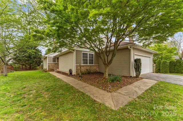 a view of a house with a yard and large tree