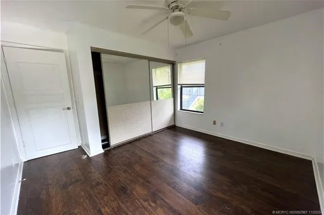 an empty room with wooden floor fan and windows
