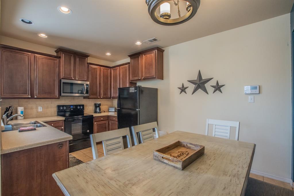 6801 Sandshell Boulevard Fort Worth, TX 76137 - Photo 7 of 28 a kitchen with stainless steel appliances granite countertop a refrigerator oven a sink a stove a dining table and chairs with wooden floor