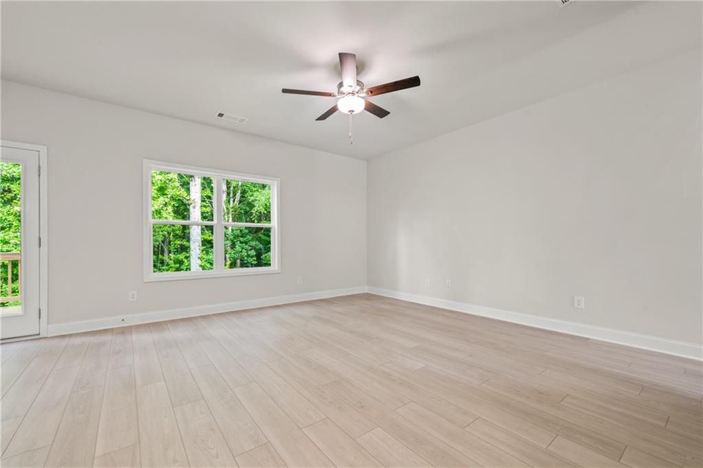 32 Station Overlook Way Auburn, GA 30011 - Photo 8 of 38 an empty room with wooden floor chandelier fan and windows