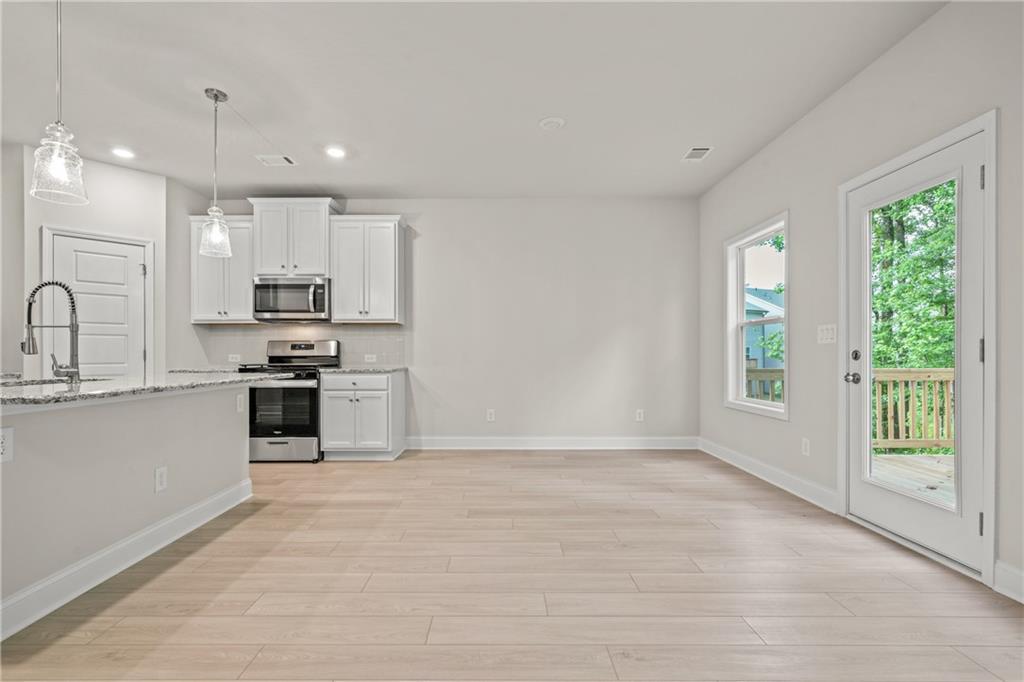 32 Station Overlook Way Auburn, GA 30011 - Photo 9 of 38 a kitchen with stainless steel appliances kitchen island granite countertop a stove a sink and a microwave