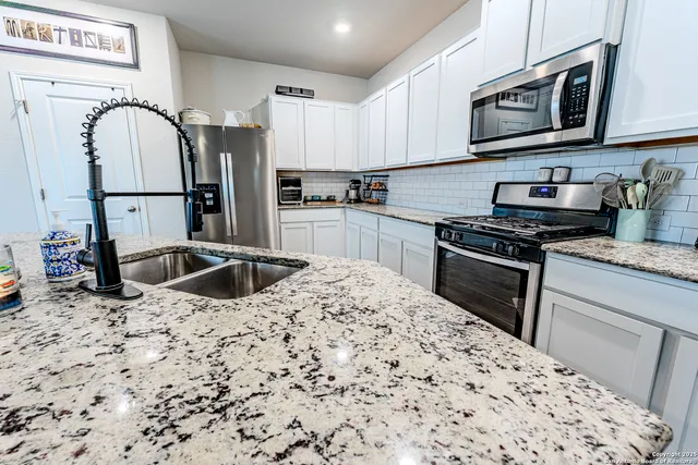 a kitchen with stainless steel appliances kitchen island granite countertop a stove a sink and a microwave