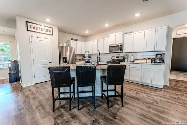 a kitchen with kitchen island a dining table chairs and white cabinets