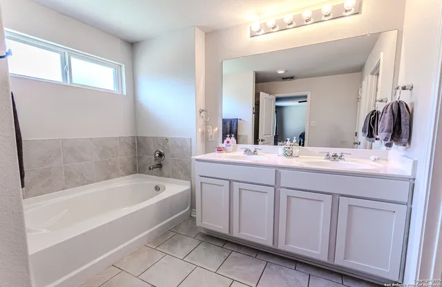 a bathroom with a tub a sink and a mirror