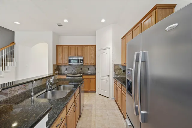 a kitchen with stainless steel appliances granite countertop a sink stove and refrigerator