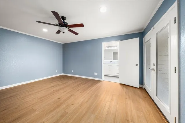 a view of an empty room with wooden floor and a ceiling fan