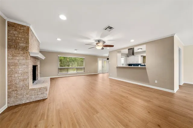 an empty room with wooden floor and a kitchen