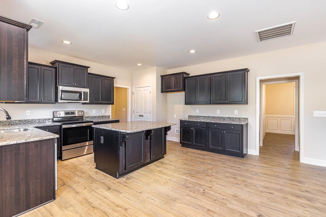 426 Jackson Pond Drive Smithfield, NC 27577 - Photo 10 of 32 a kitchen with stainless steel appliances granite countertop a stove top oven a sink dishwasher and a microwave oven with wooden floor