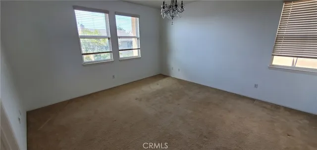 an empty room with a windows and chandelier fan