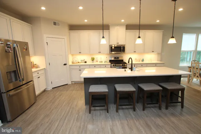 a kitchen with stainless steel appliances granite countertop a kitchen island hardwood floor sink and stove