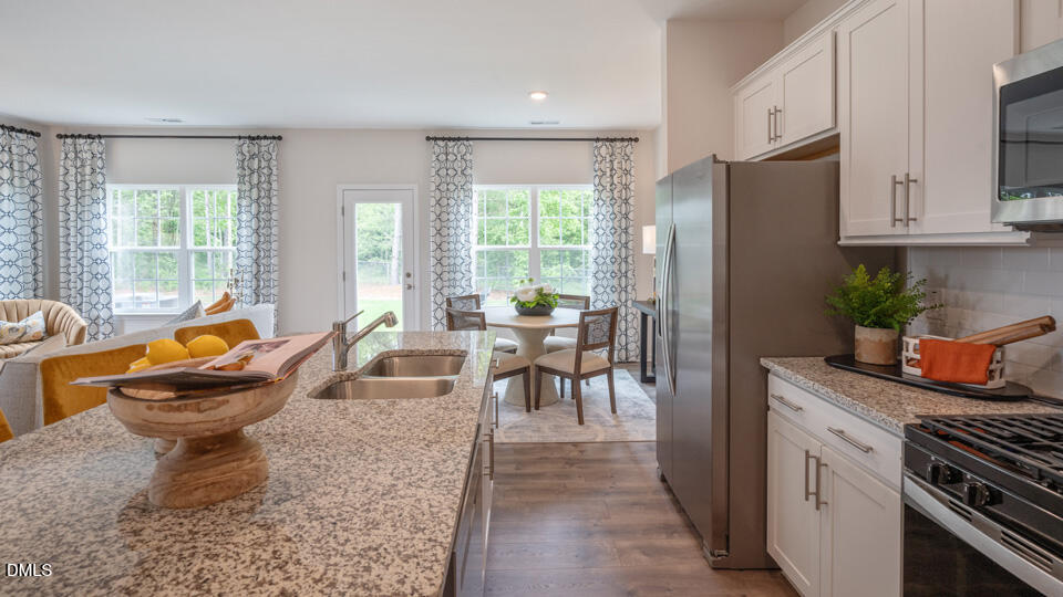 304 Perseus Street Angier, NC 27501 - Photo 11 of 34 a dining room with stainless steel appliances granite countertop a couch a table and chairs with wooden floor