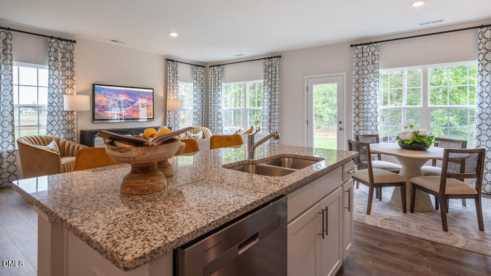 304 Perseus Street Angier, NC 27501 - Photo 12 of 34 a kitchen with granite countertop a table chairs and wooden floor