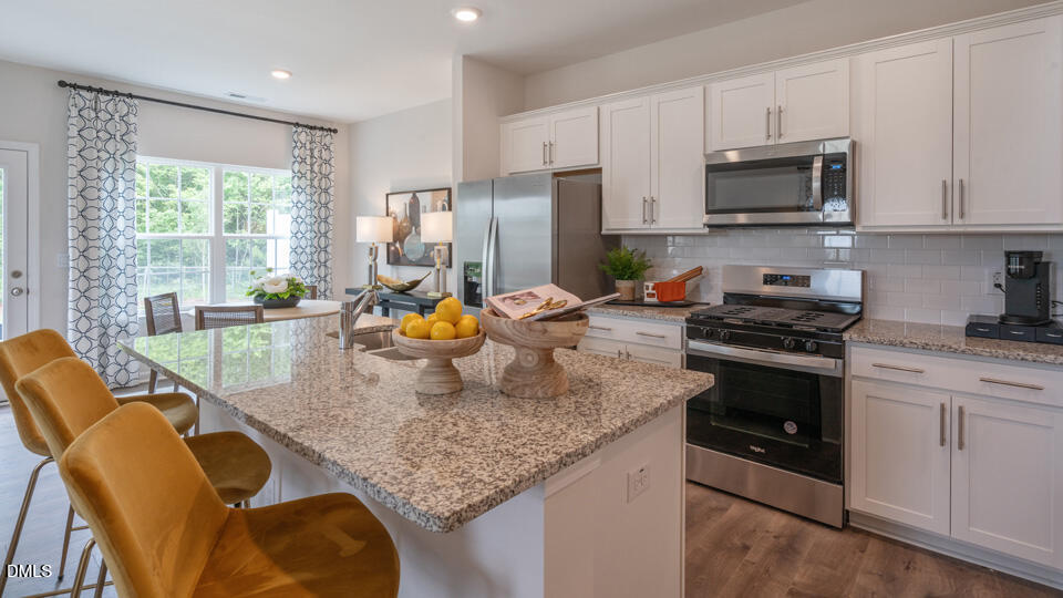 304 Perseus Street Angier, NC 27501 - Photo 10 of 34 a kitchen with stainless steel appliances granite countertop a stove a sink a microwave and dining table