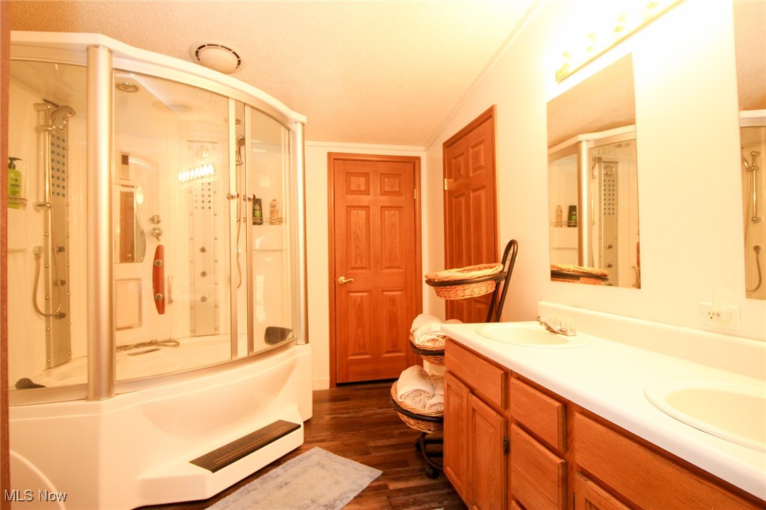 1798 Campbell Road Southwest New Philadelphia, OH 44663 - Photo 24 of 50 Bathroom featuring combined bath / shower with glass door, hardwood / wood-style floors, ornamental molding, and vanity