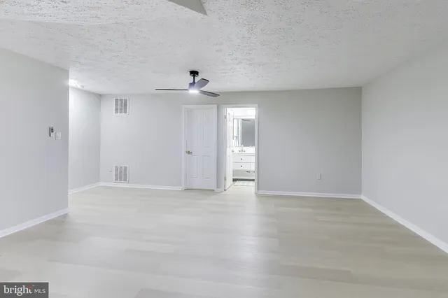 an empty room with ceiling fan and window