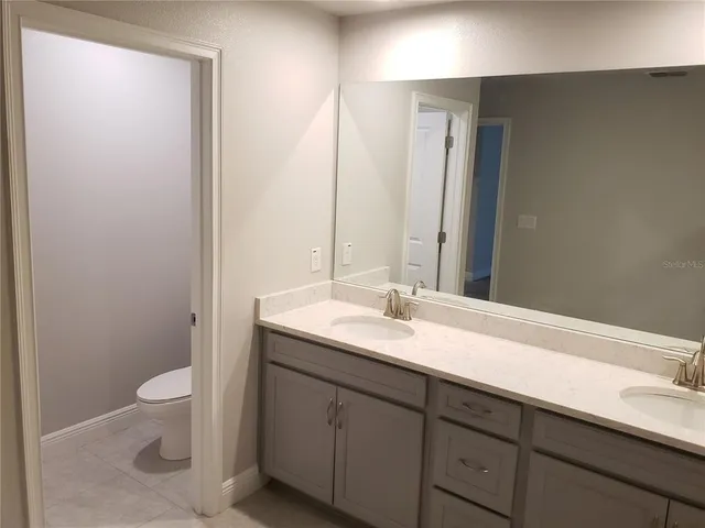 a bathroom with a granite countertop sink a toilet and a mirror