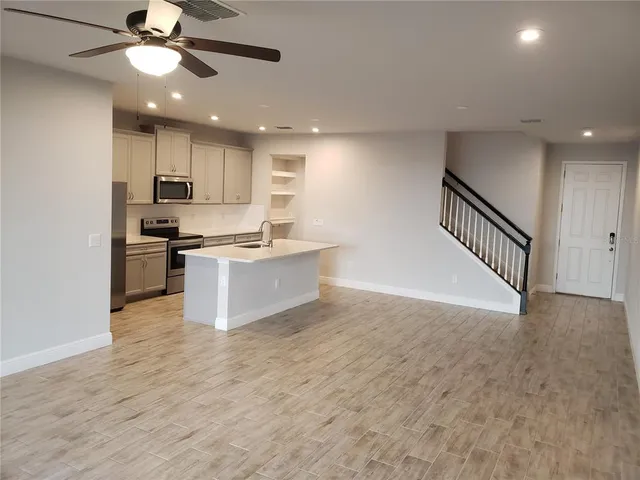 a view of kitchen with kitchen island wooden floor and stainless steel appliances