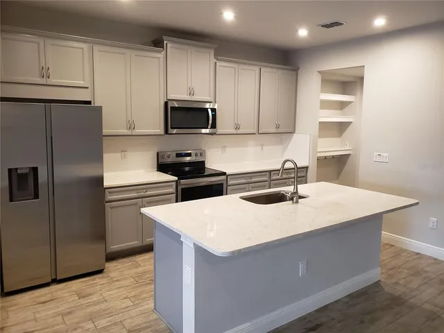 a kitchen with stainless steel appliances granite countertop a refrigerator a sink a stove a microwave and island