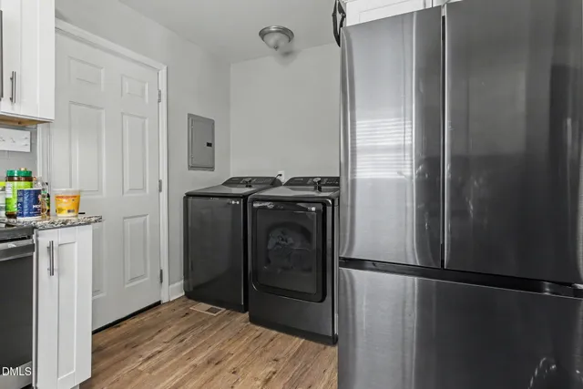 a kitchen with stainless steel appliances white cabinets a sink a stove a microwave and wooden floors