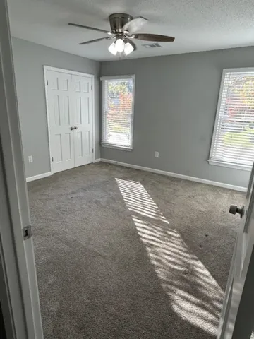 an empty room with windows and fan