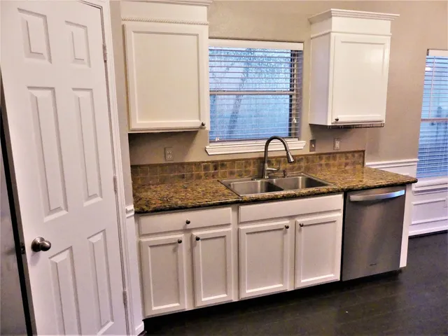 a kitchen with white cabinets and sink