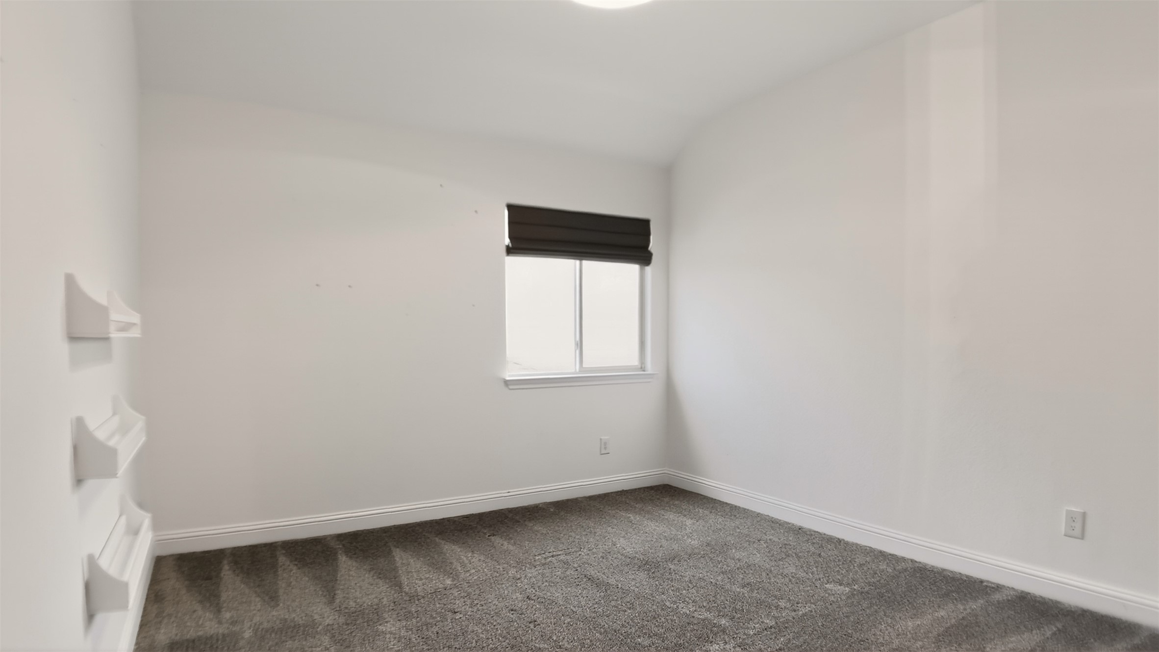 1505 Long Shadow Lane Georgetown, TX 78628 - Photo 23 of 28 Bright room featuring a window with a dark shade, plush gray carpet, white walls, white baseboards, and built-in wall shelving