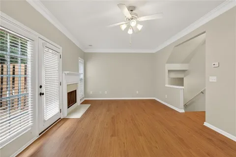 an empty room with wooden floor fireplace and windows