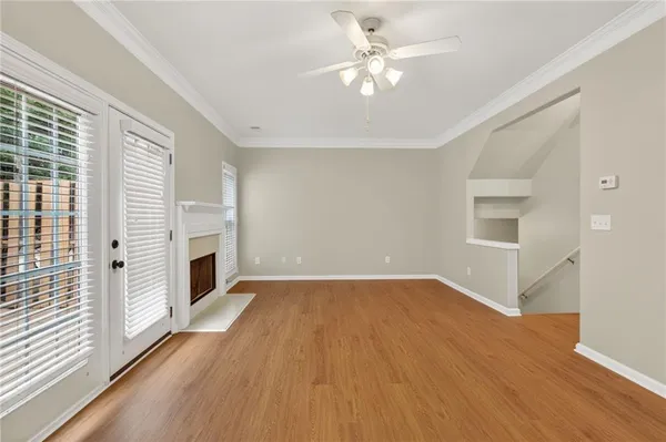 an empty room with wooden floor fireplace and windows
