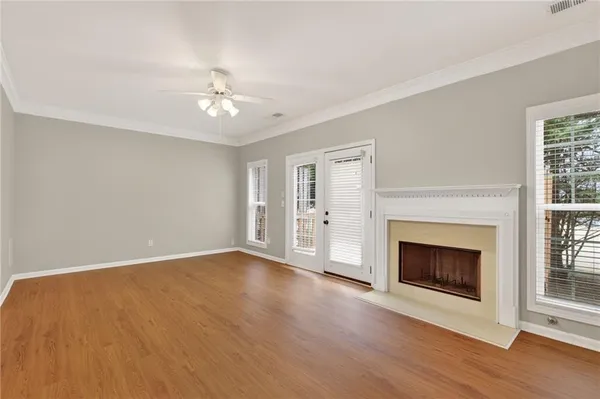 an empty room with wooden floor fireplace and windows