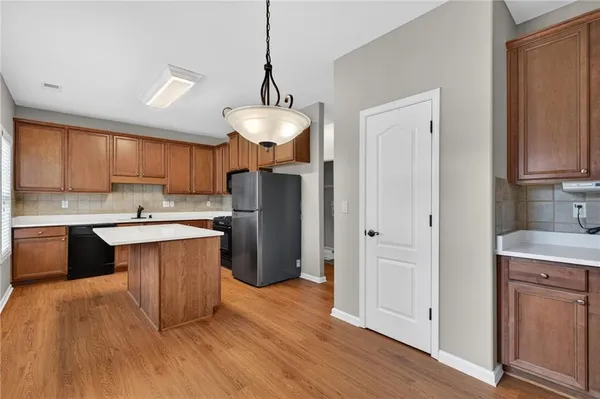 a kitchen with stainless steel appliances granite countertop a refrigerator a sink dishwasher a stove and a wooden floor