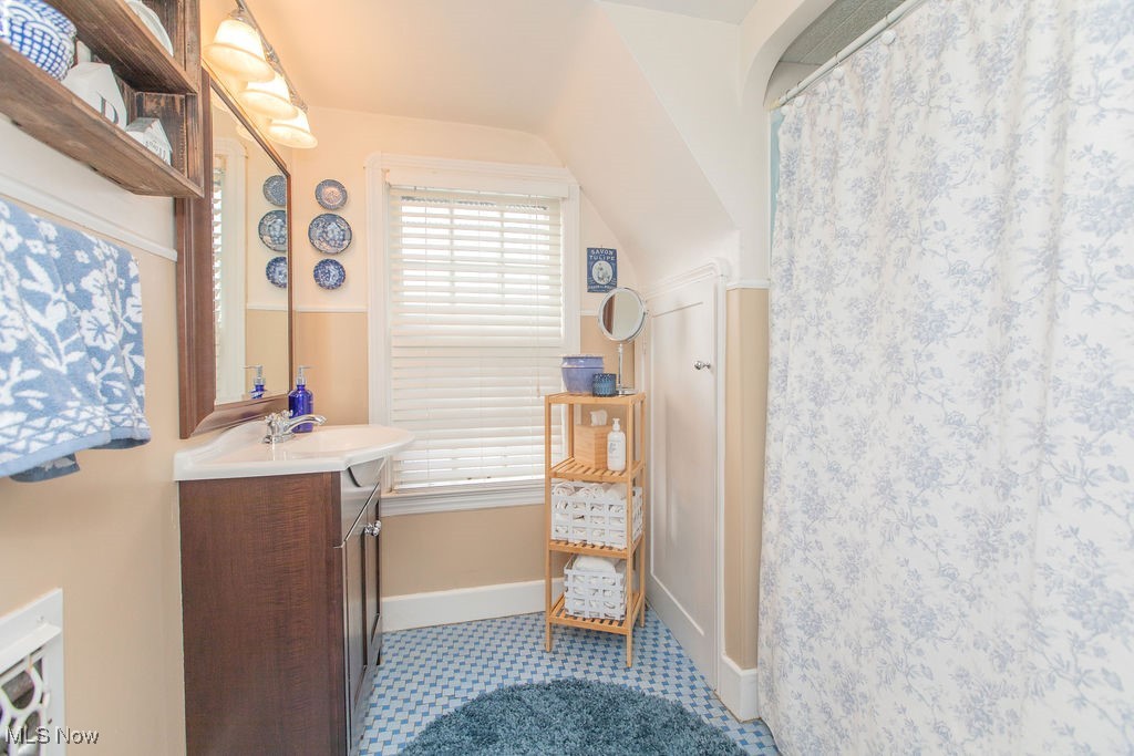 1528 Oakmount Road South Euclid, OH 44121 - Photo 20 of 24 Full bath on the second floor with original blue ceramic tile flooring, an updated wood vanity with a white sink, wood mirror, overhead lighting, toilet, and tub/shower.