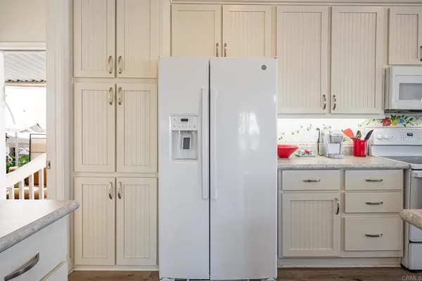 a kitchen with a sink a refrigerator and white cabinets