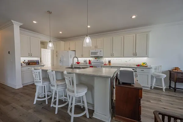 a kitchen with stainless steel appliances granite countertop a table chairs sink refrigerator and cabinets