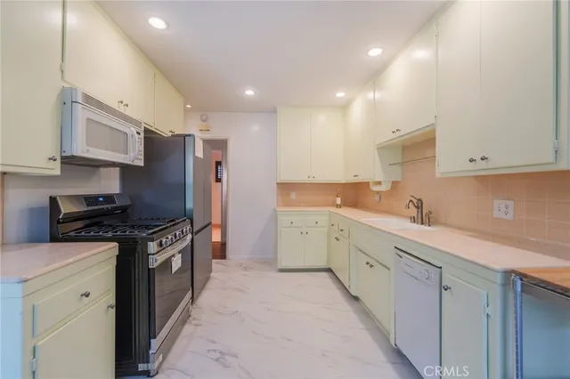 a kitchen with stainless steel appliances granite countertop a stove a sink and a refrigerator