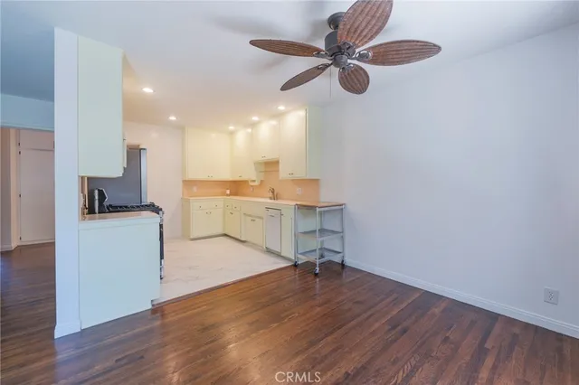 a view of kitchen and empty room with wooden floor