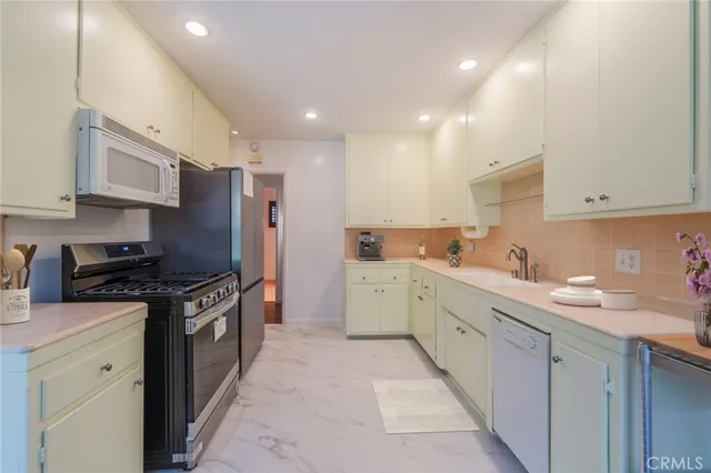 a kitchen with stainless steel appliances granite countertop a sink stove refrigerator and cabinets