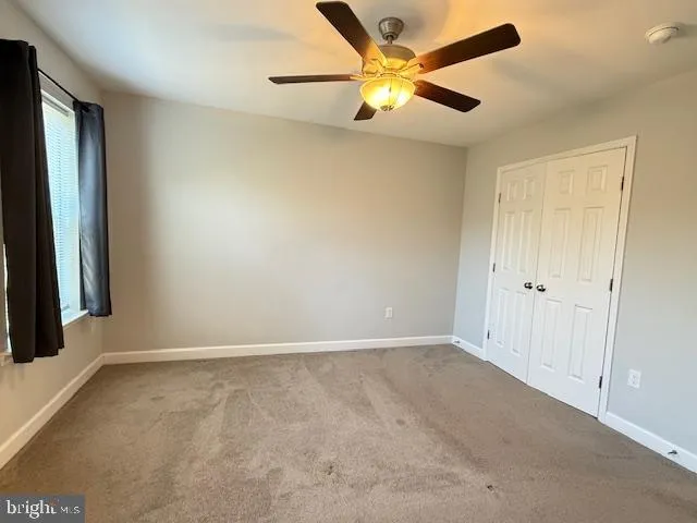 an empty room with a window and a fan