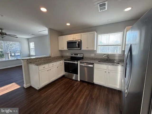 a kitchen with granite countertop a refrigerator stove top oven and sink