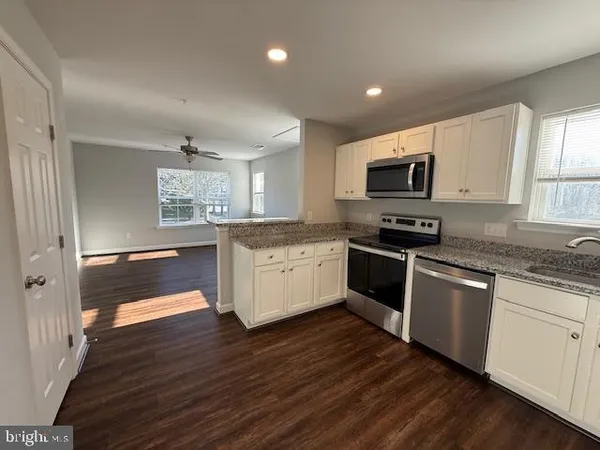 a kitchen with kitchen island granite countertop a sink cabinets and stainless steel appliances