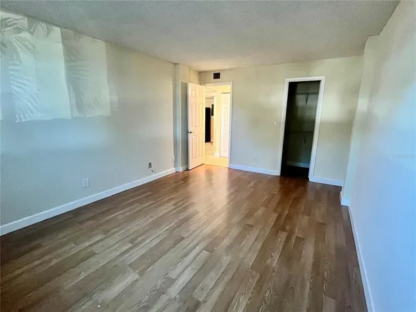 a view of an empty room with wooden floor and closet